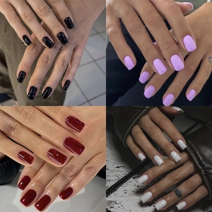Detail view of four glossy press-on nail colors including black, purple, red, and pearl white