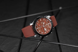 Detail of silver stainless steel watch with brown silicone strap and textured dial