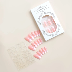 Makroansicht langer rosa französischer Kunstnägel mit Strasssteinen in Papierverpackung