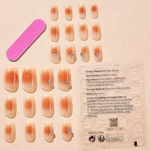 Short orange gradient press-on nails set with rhinestone flowers and manicure tools
