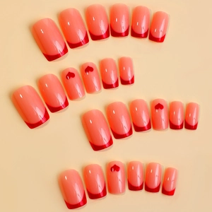 Detail von glänzenden Press-on-Nägeln mit roten French-Tips und Herzmustern auf Rosa