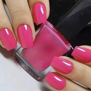 Macro shot of glossy rose pink nail polish in square bottle with smooth mirror finish