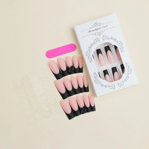 Close-up of French press-on nails with black matte tips and 3D bow details in packaging