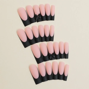 Long coffin press-on nails with matte pink base, black French tips and 3D bow accents