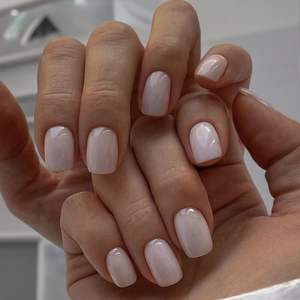 Detail of glossy milky white short square nails with a smooth and polished finish