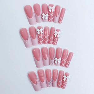 Pink ballet-style press-on nails with white bows, pearls, and criss-cross bandage design