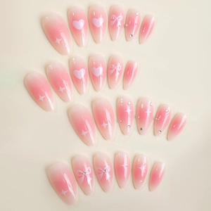 Pink heart and bow almond press-on nails with sparkling rhinestones and gradient finish