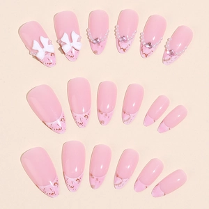 Pink almond press-on nails with 3D bows, pearls, and gold foil marble details