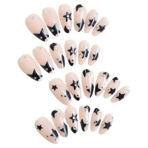 Almond-shaped press-on nails in nude pink with black stars and shiny rhinestones