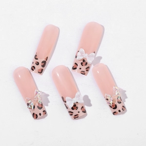 Long ballet press-on nails with nude pink base, leopard print tips, and 3D bow charms
