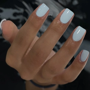 Close-up of glossy light blue square handmade press-on nails on a person's hand