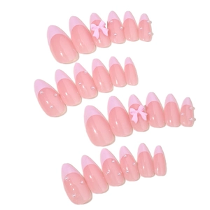 Faux ongles amande rose style French avec nœuds 3D et perles sur fond blanc pur