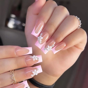 Long square press-on nails with pink French gradient and 3D white floral accents
