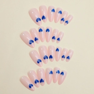 Detail of 24-piece set almond press-on nails in soft pink with blue heart patterns