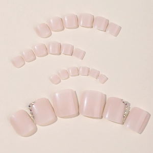 Short press-on toenails in nude pink with rhinestone accents and glossy finish