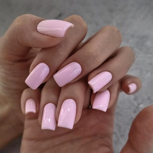 Close-up of handmade glossy pale pink rectangular press-on nails on dark stone texture