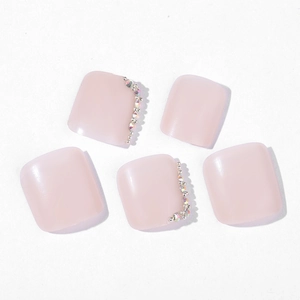 Glossy light pink press-on toe nails with delicate rhinestone edge and silver bead detail