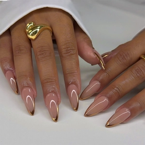 Detailed view of almond shape nude pink nails with metallic gold French tips on model hand