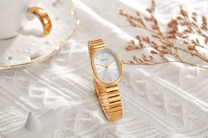 Elegant gold oval quartz watch resting on white knit fabric with lifestyle background