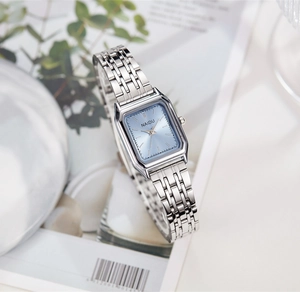 Détail d'une montre carrée en acier argenté avec cadran bleu clair sur magazine