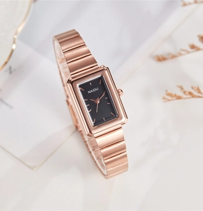 Detail shot of rectangular rose gold quartz watch with black dial on marble background