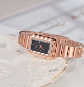 Close-up of elegant rectangular rose gold watch featuring a sleek black dial and metal strap