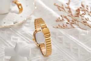 Detail of elegant gold link strap and folding clasp on women quartz watch with silver back