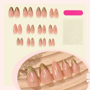 Faux ongles amande rose avec bordure dorée française et motifs d'étoiles sur bois