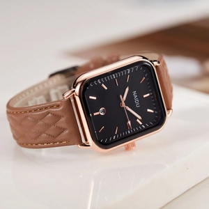Macro shot of rectangular rose gold watch case with brown quilted leather strap texture