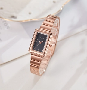 Detail of elegant rectangular rose gold quartz watch with black dial on marble background
