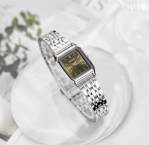 Détail d'une montre à quartz carrée avec bracelet en acier sur fond de marbre
