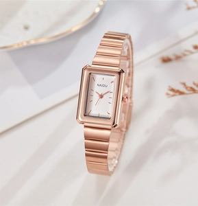 Macro shot of rectangular rose gold watch with brushed metal texture and white dial