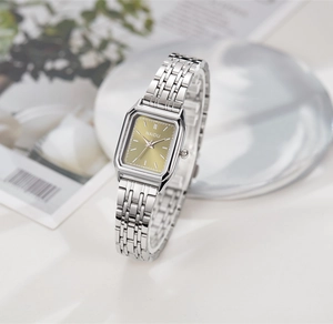 Vue détaillée d'une montre carrée en acier argenté avec cadran doré minimaliste