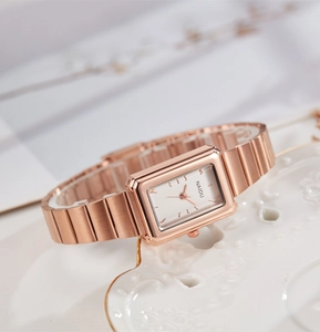 Close-up of rose gold rectangular quartz watch for women on a white textured plate
