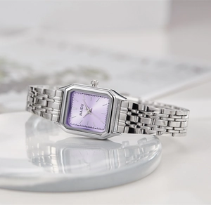 Détail d'une montre à quartz argentée avec cadran violet et bracelet en métal sur marbre
