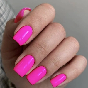 Close-up of bright fluorescent pink square-oval handmade nails with a glossy mirror finish