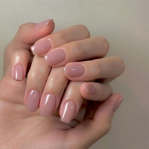 Close-up of glossy nude pink handmade press-on nails in medium coffin shape