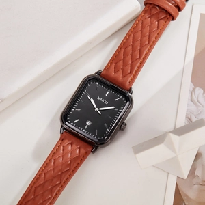 Detailed close-up of rectangular quartz watch with date window and brown quilted leather strap