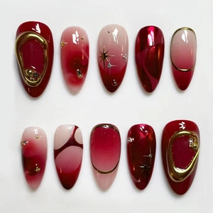 Flat lay of red and pink almond press-on nails with 3D gold details and marble pattern