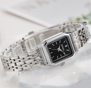 Détail d'une montre à quartz carrée argentée avec cadran noir sur fond de marbre