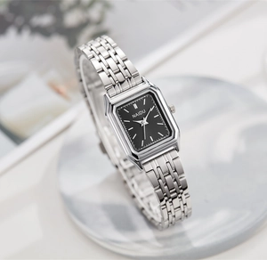 Détail d'une montre carrée noire avec bracelet en métal argenté sur du marbre