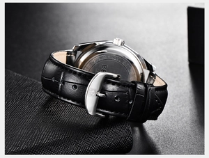 Détail du fond de boîtier en acier et du bracelet en cuir noir avec boucle logo