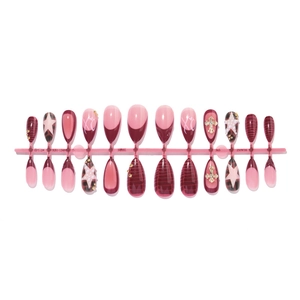 Almond press-on nails in burgundy and pink with gold stars and cross charms