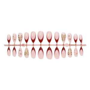 Almond French fake nails with cherry red tips, gold bows, and sparkling star accents