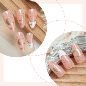 Faux ongles amande avec base rose, French tips et motifs dorés de lune et d'étoiles