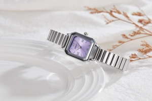 Detail of square purple dial watch with Roman numerals and silver metal link strap