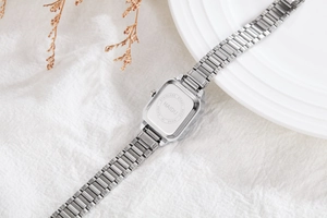 Polished stainless steel caseback of a square watch with NAIDU logo and metal strap