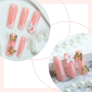 Long coffin press-on nails with pink french tips, white bows and glitter butterfly charms