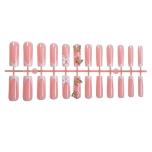French tip press-on nails in pale pink with 3D white bows and rhinestone butterflies