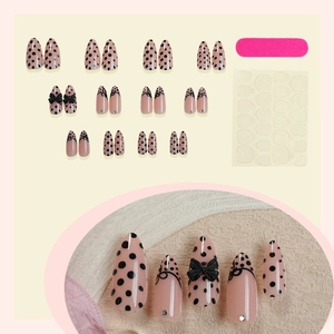 French almond press-on nails with nude pink base black polka dots and 3D bowknot accents